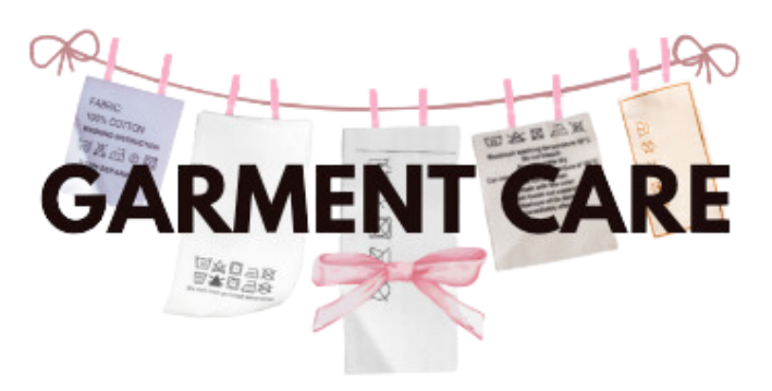 The image shows the words "GARMENT CARE" prominently in the center with various clothing care labels hanging on a line above the text. The labels are attached with pink clothespins, and one of them is adorned with a pink bow. The labels feature care instructions in different languages and symbols, representing the diverse information found on clothing tags regarding proper maintenance and care.