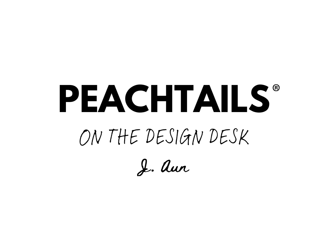  The image shows the text "PEACHTAILS®" in bold, capital letters at the top, followed by "ON THE DESIGN DESK" in a handwritten script font. Below this phrase is a signature that reads "J. Aun," suggesting the name of the person on the design desk or the author of the text. The background is plain, emphasizing the text.